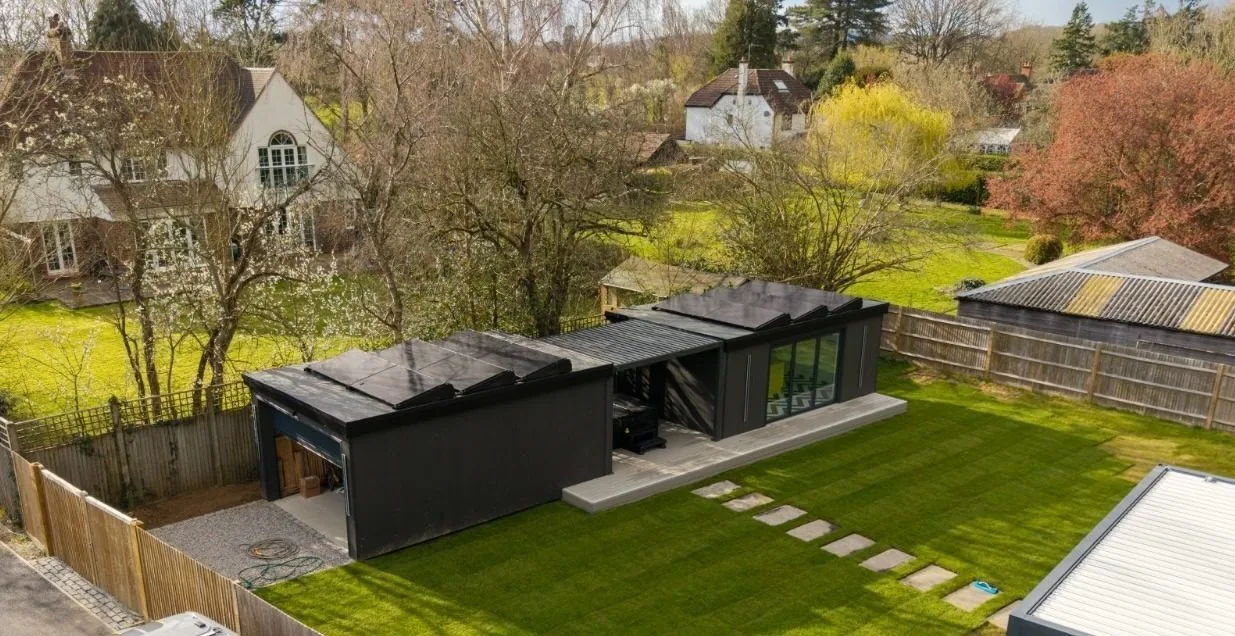 Aerial view of a black-clad insulated garden studio with solar panels and landscaped garden by Cruise Garden Rooms